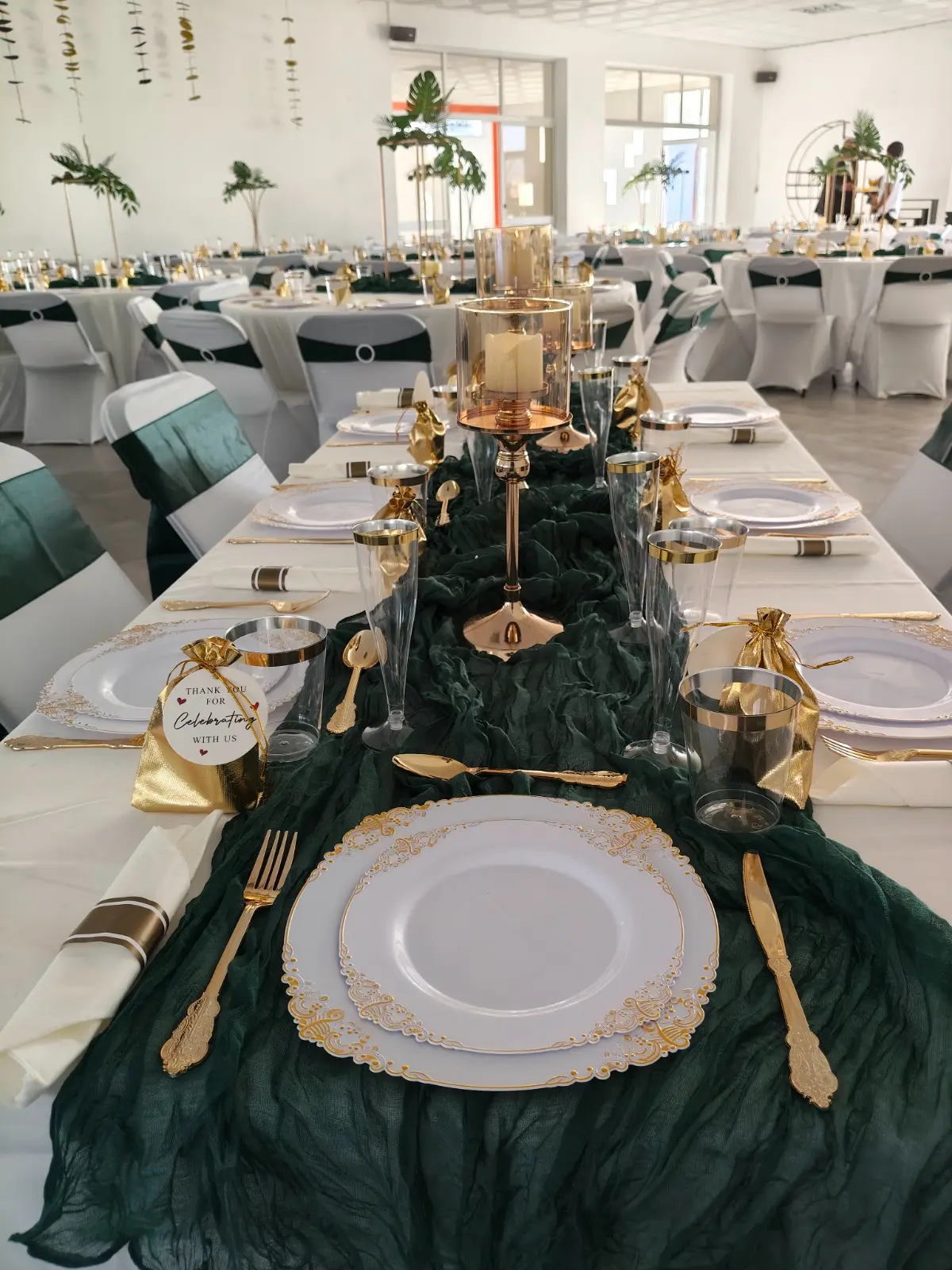 Mesa de banquete formal com passadeira verde, pratos brancos com rebordos dourados e taças de cristal. Espargos, Ilha do Sal, Cabo Verde.
