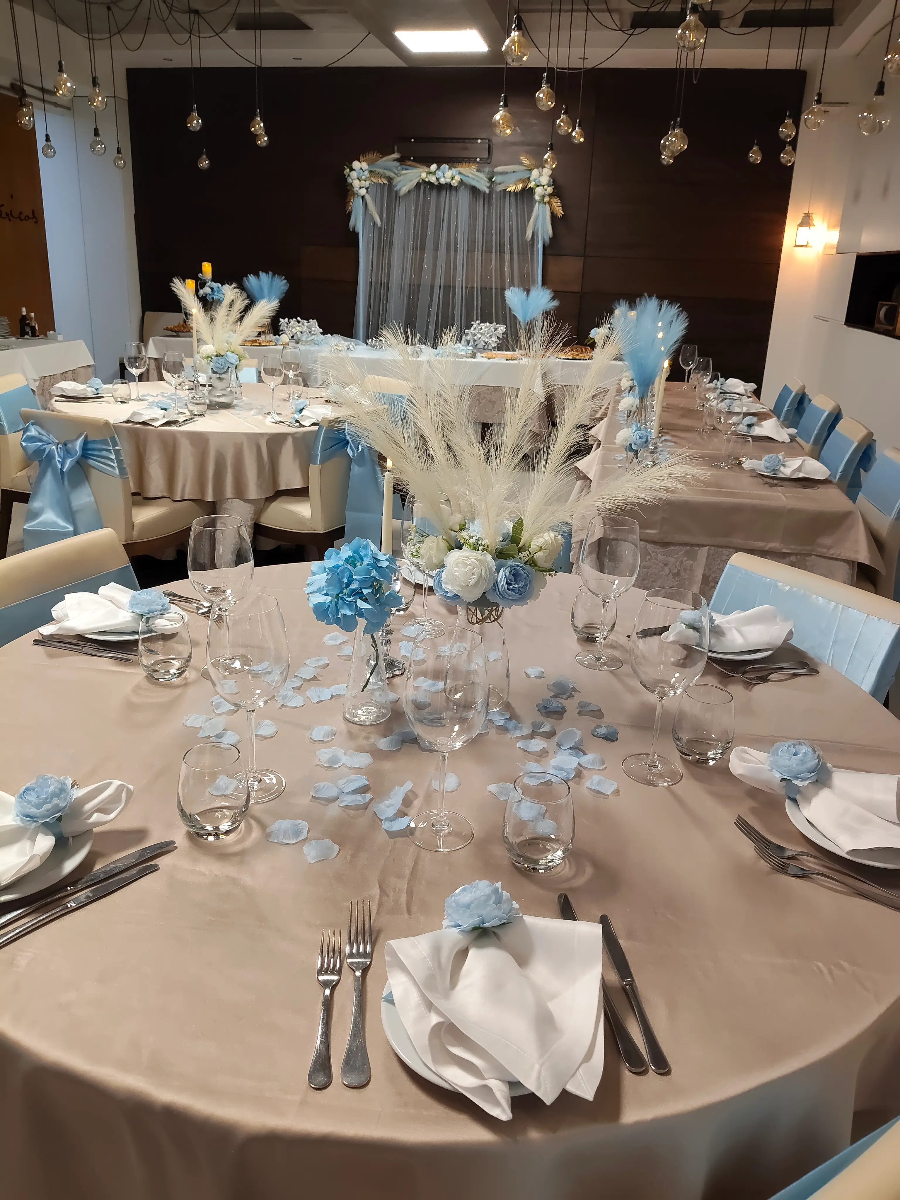 Mesa de jantar formal decorada para evento com fitas em azul-claro, rosas brancas e pétalas espalhadas. Espargos, Ilha do Sal, Cabo Verde.