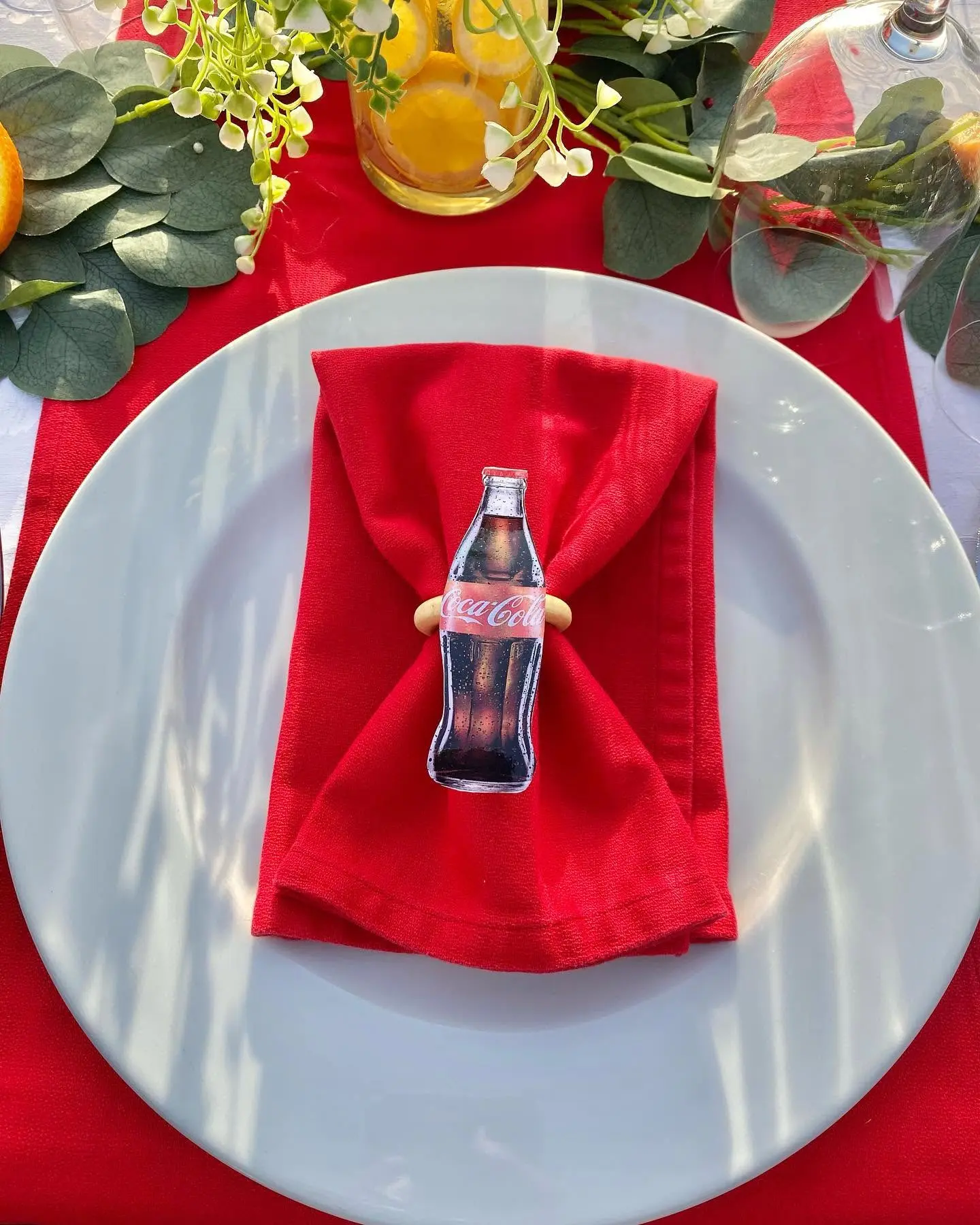 Detalhe de prato branco com guardanapo vermelho preso por um porta-guardanapo em formato de garrafa de Coca-Cola. Santa Maria, Ilha do Sal, Cabo Verde.
