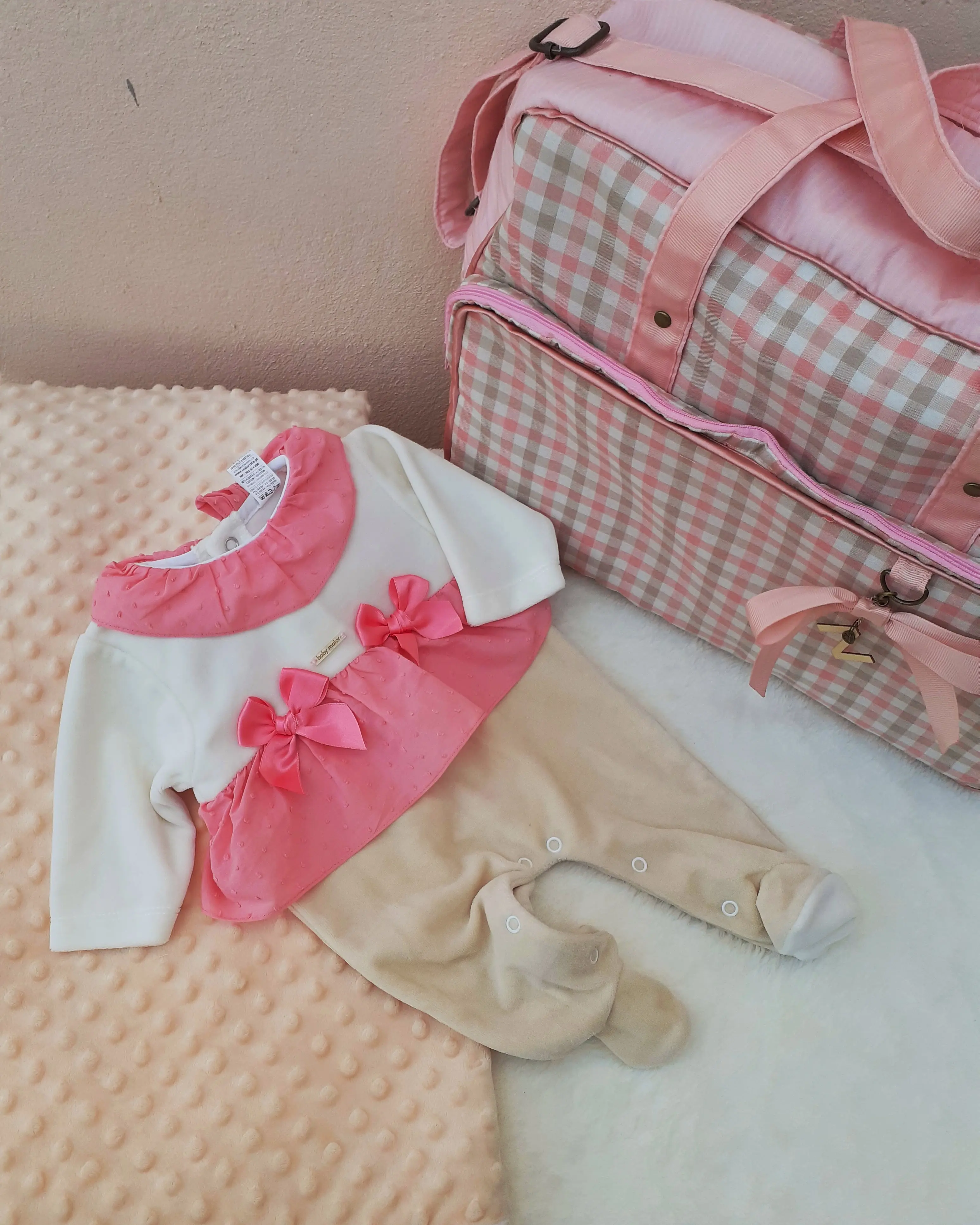Muda-fraldas para bebé em rosa e branco com saco de maternidade aos quadrados e roupinha com laços. Ilha do Sal, Cabo Verde.