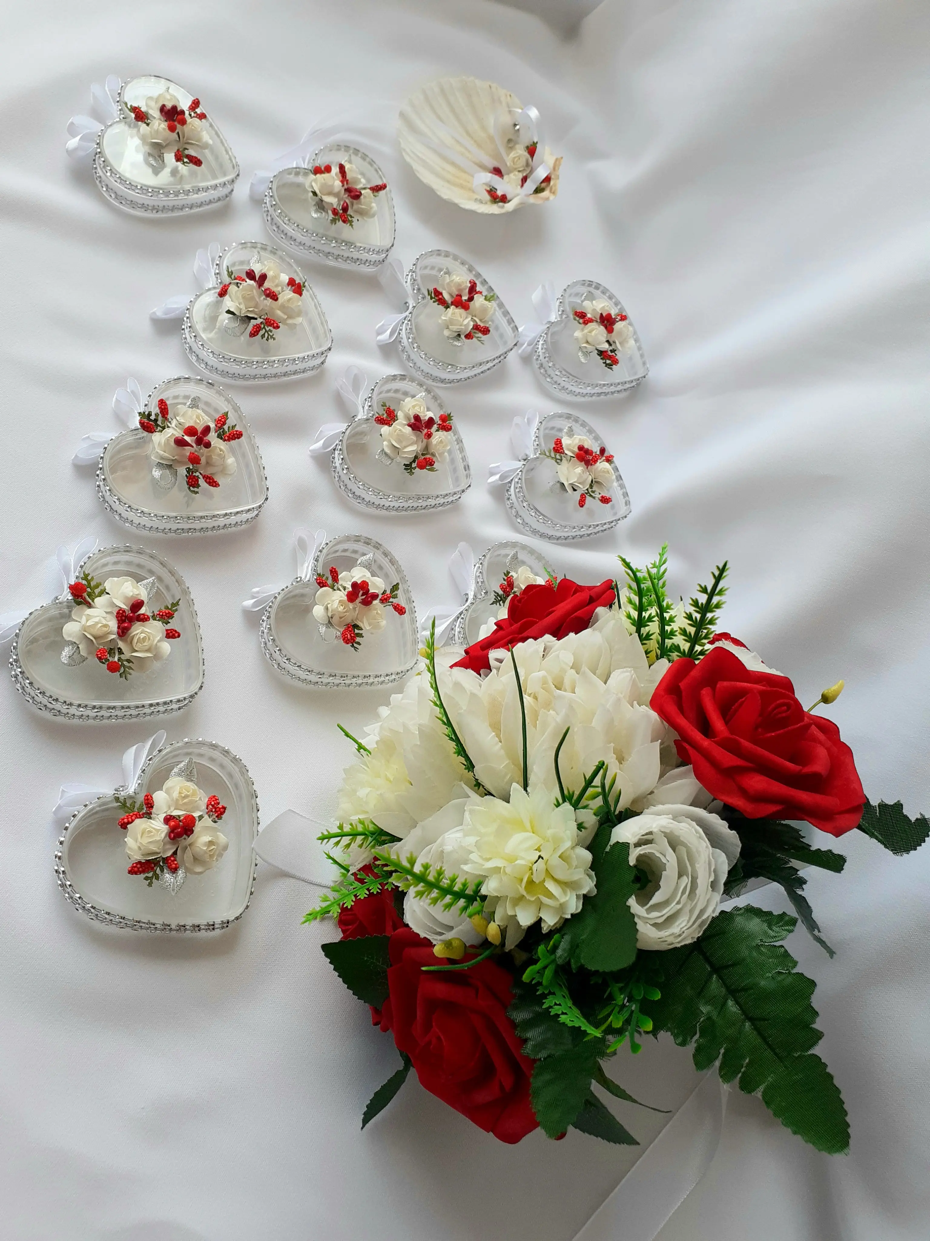 Caixas de lembranças transparentes em formato de coração com miniflores, junto a um bouquet de rosas vermelhas e brancas. Ilha do Sal, Cabo Verde.