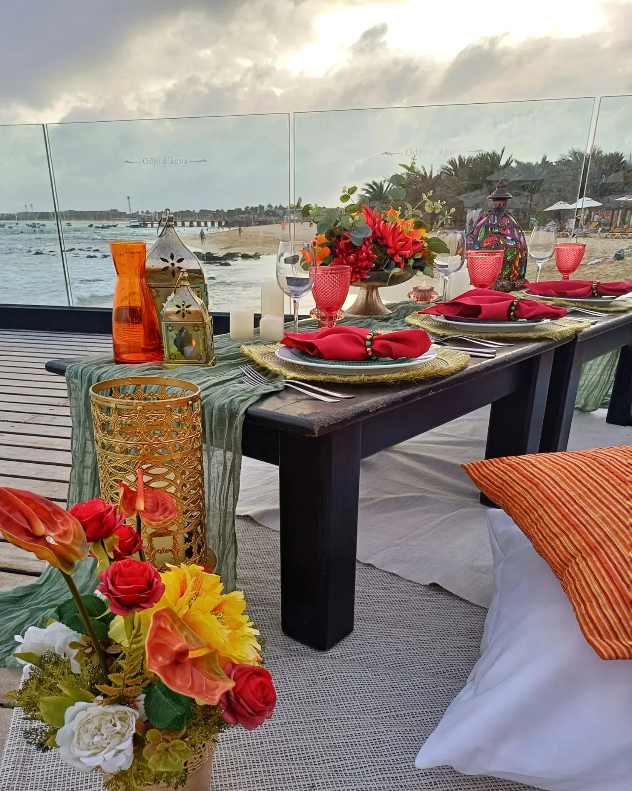 Mesa baixa posta para piquenique romântico com almofadas, lanternas e flores na esplanada sobre o mar, na praia de Santa Maria, Ilha do Sal, Cabo Verde.