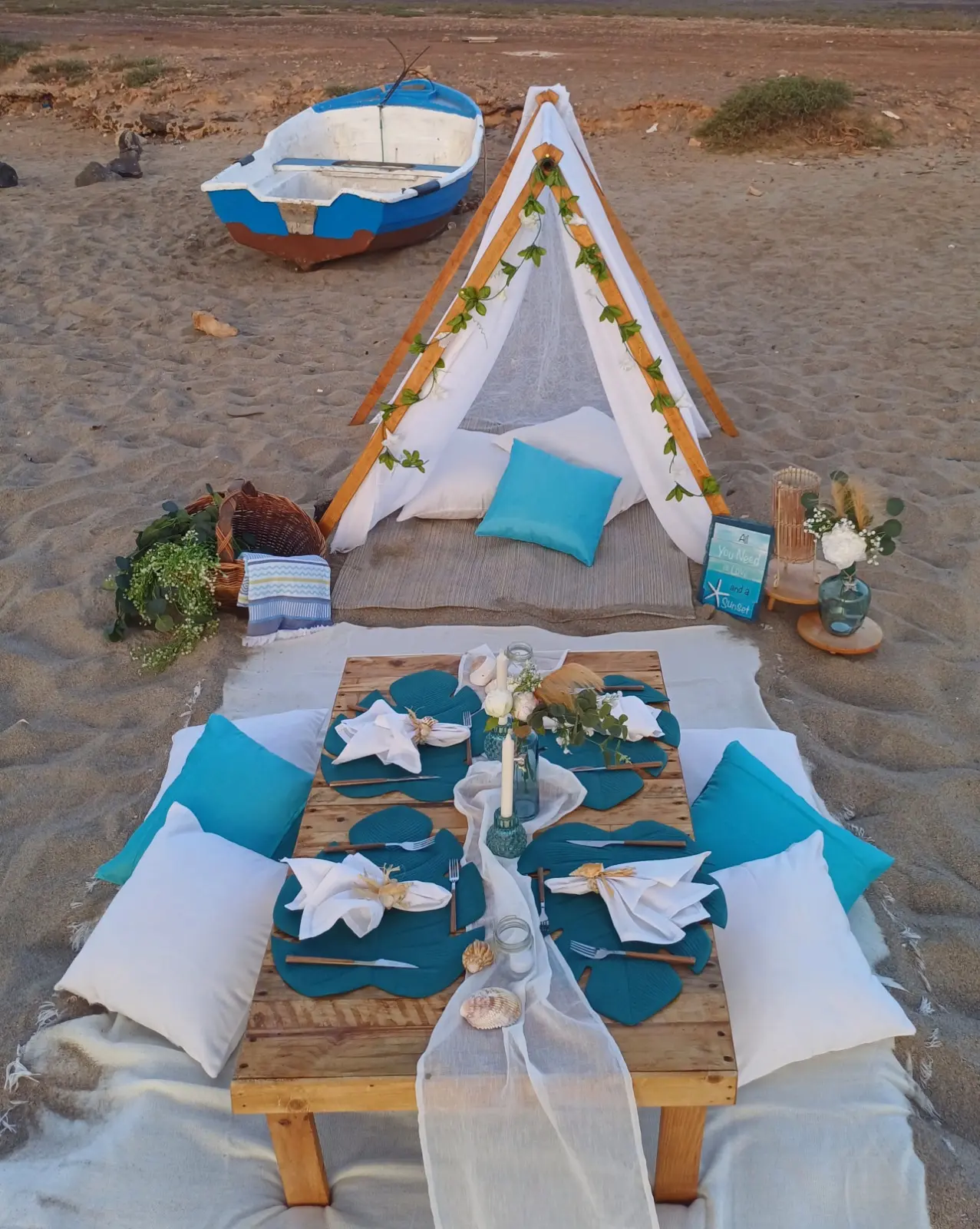 Mesa baixa posta para piquenique romântico ao pôr do sol na praia da Calheta Funda. Ilha do Sal, Cabo Verde.