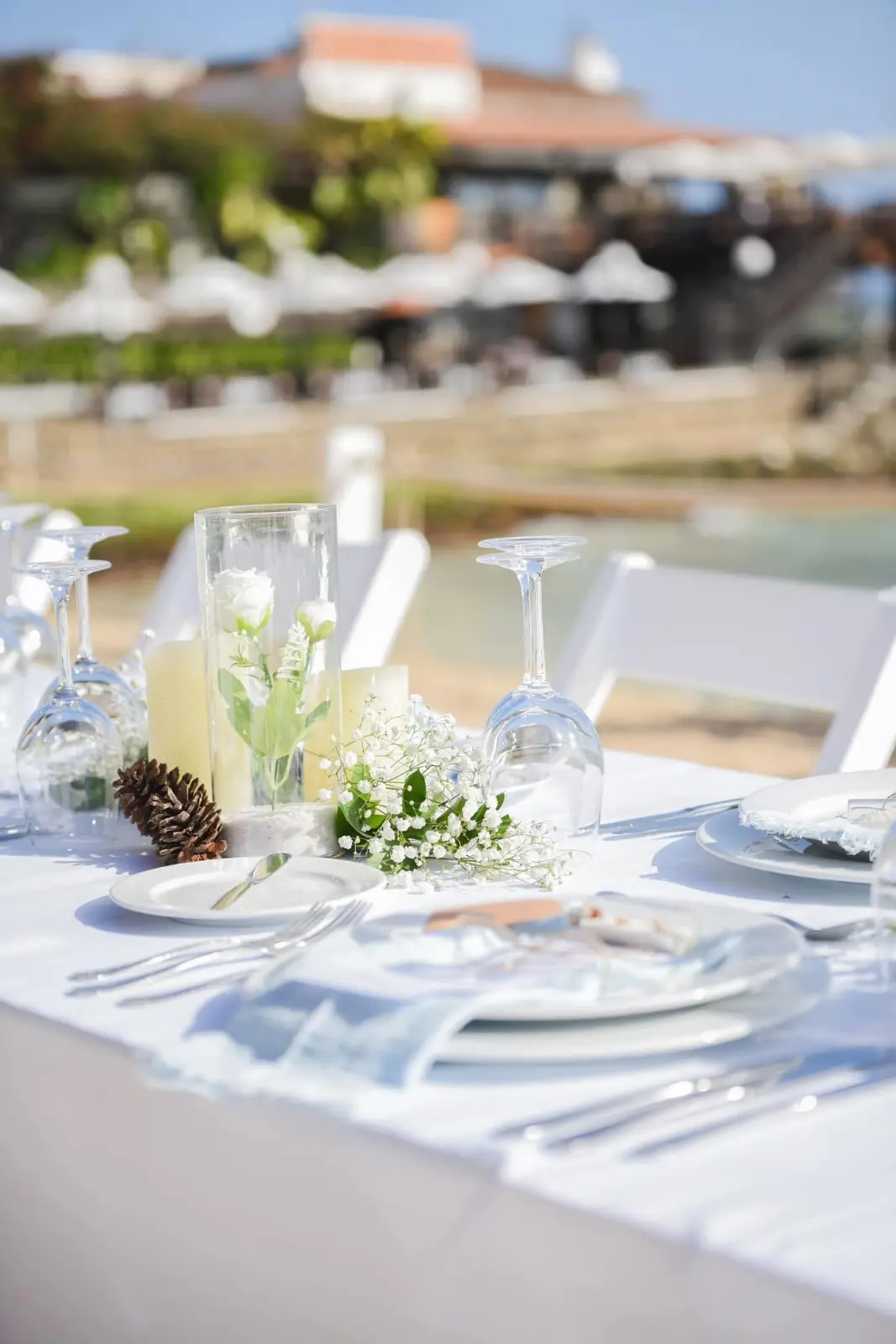 Decoração de centro de mesa de casamento com arranjo floral, velas e pinha à beira-mar em Santa Maria, Ilha do Sal, Cabo Verde.