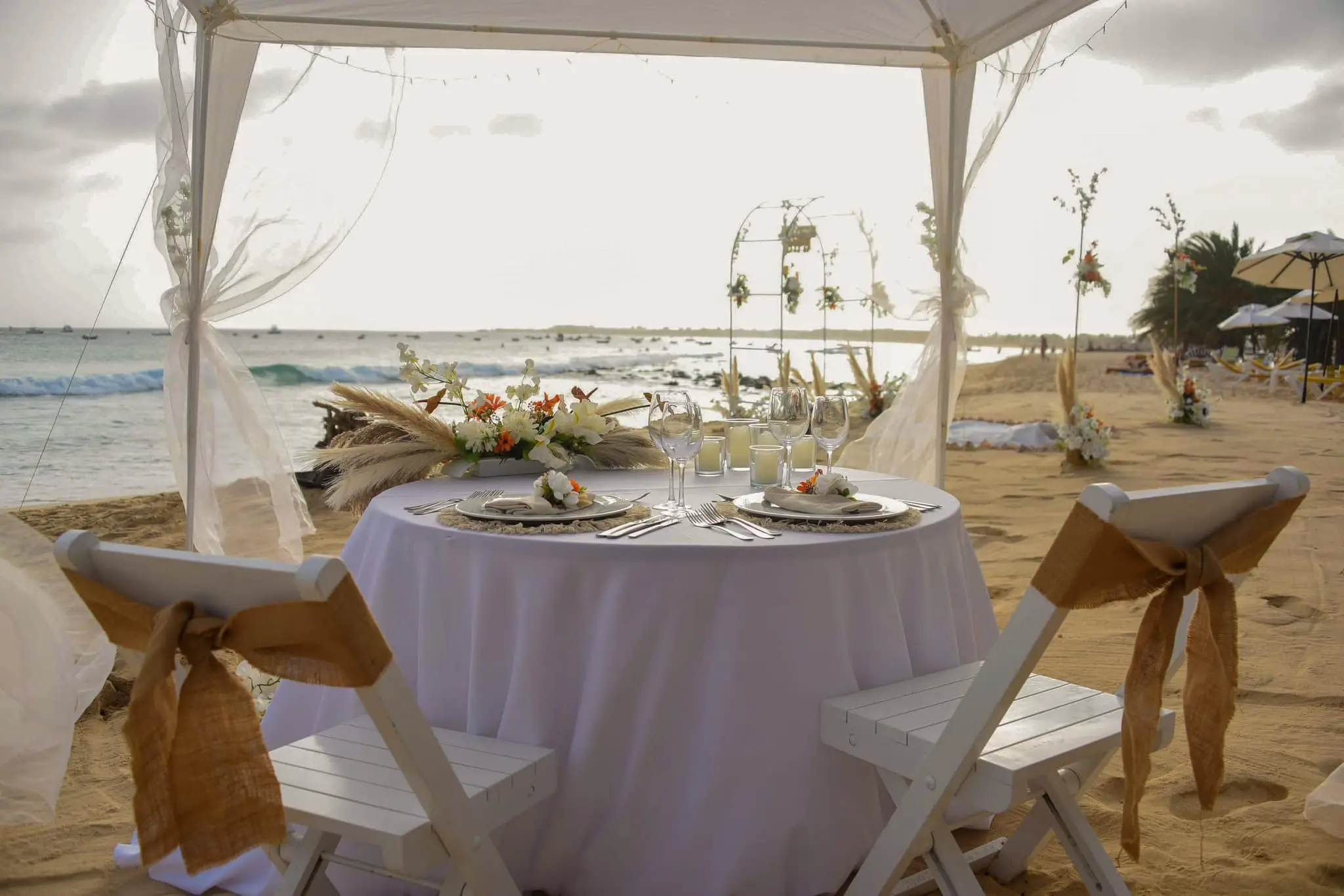 Mesa de jantar romântica para casal decorada na praia sob uma tenda com vista para o mar em Santa Maria, Ilha do Sal, Cabo Verde.