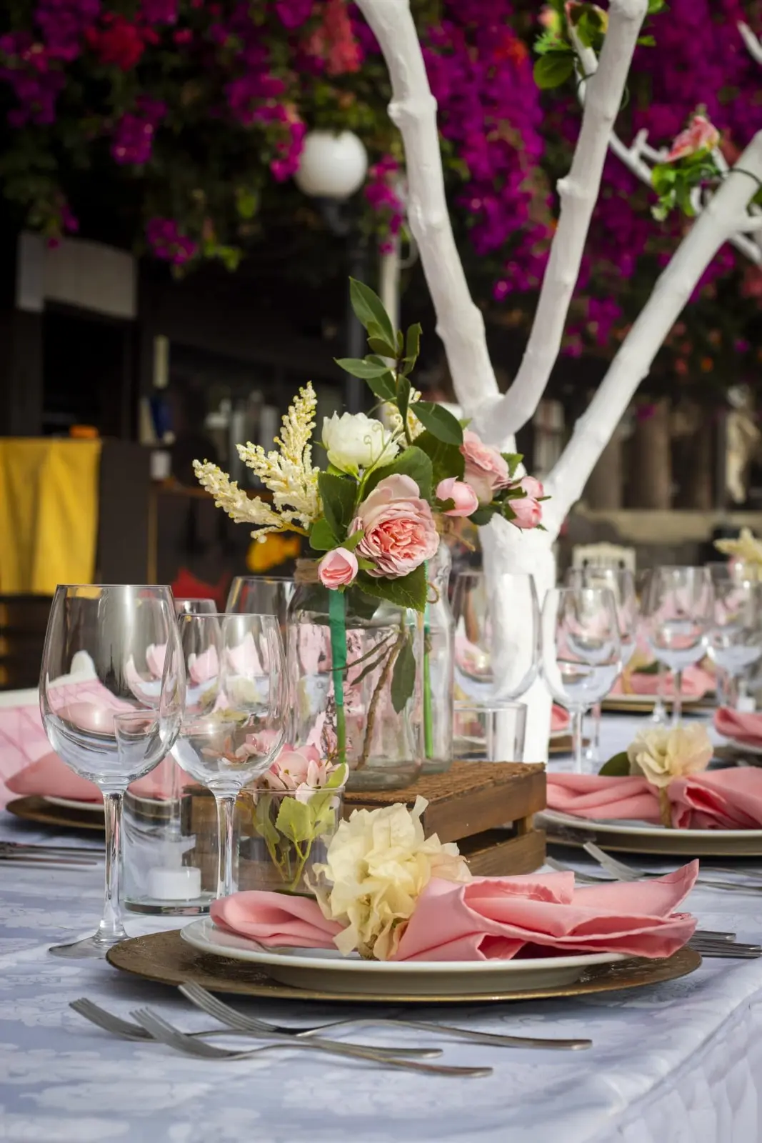 Decoração de mesa de casamento com flores em tons de rosa, guardanapos a condizer, caixotes de madeira e copos de cristal. Ilha do Sal, Cabo Verde.